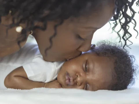 A mother kisses her newborn infant.