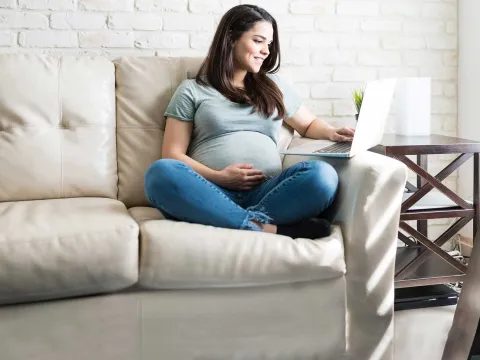 An expectant mother has a video call on her computer. 