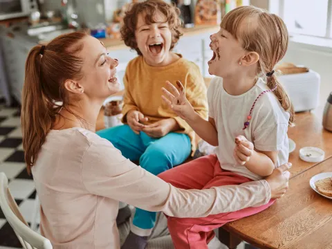 A mom laughs her way through a messy lunch with her kids.