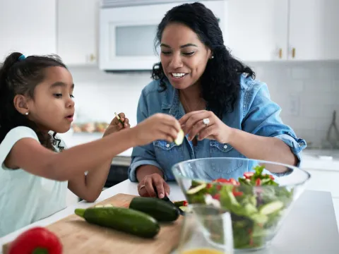 A mother and daughter making a salad together.