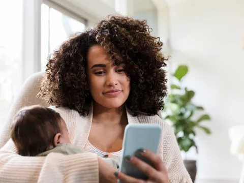 Mother holding baby while on a cell phone