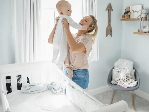 A mom lifts her infant out of the crib.