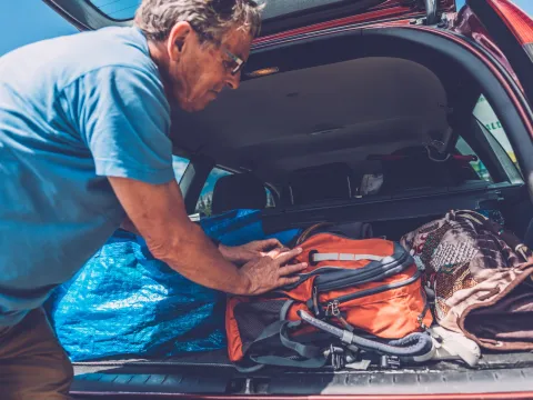 A man packs his belongings in the trunk of his car.