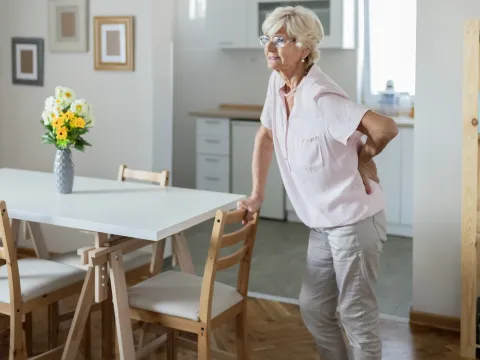 A woman experiencing lower back pain in her home.