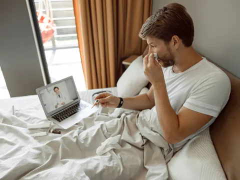 A young man has a remote check up with his doctor from home