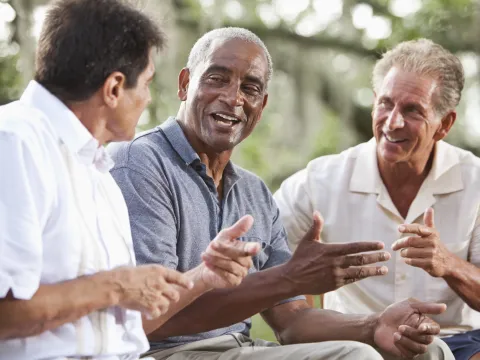 Three men have a conversation outdoors.