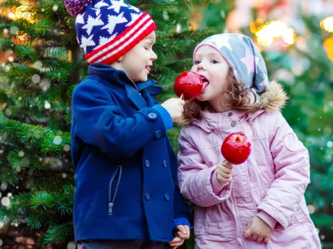 Two children at candy apples near the holidays.