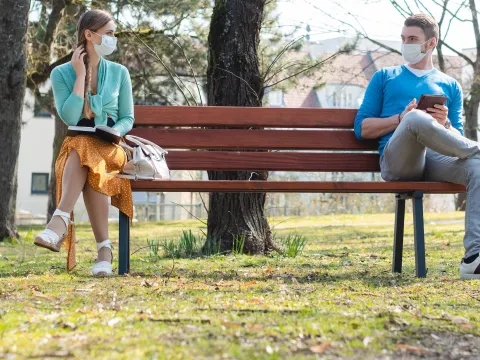 Two people keeping their distance on a park bench.