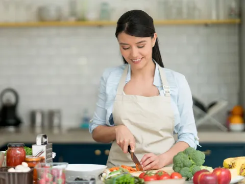 A Young Woman Chops Veggies in the Kitchen