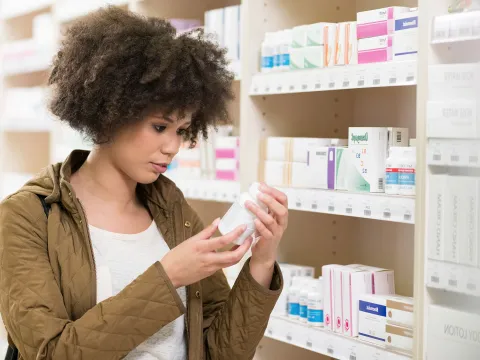 A young woman analyzing an over-the-counter medication.