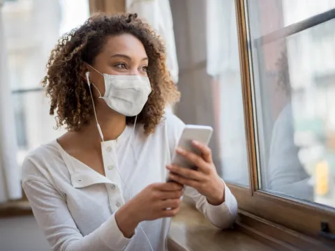 A woman wearing  face mask and using her cell phone. 