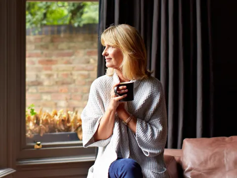 A Woman Looks at the Window with Her Cup of Tea