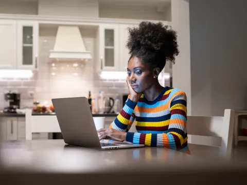 A woman in her living room and on her computer