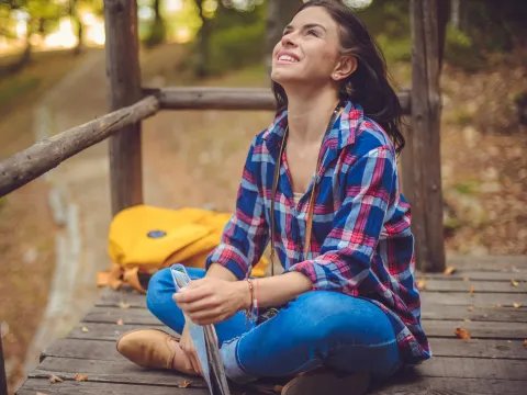 A woman takes a deep breath while sitting outside.