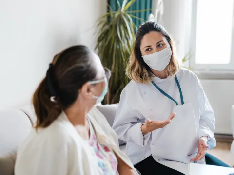 A woman speaking with her doctor wearing a mask.