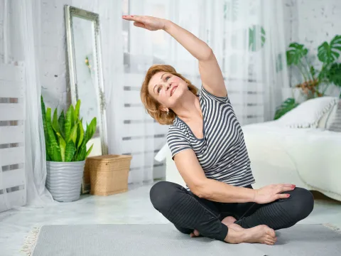 A woman stretching in her bedroom. 