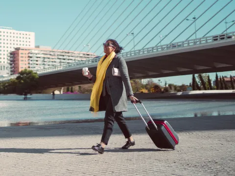 A young woman rolls her suitcase as she travels