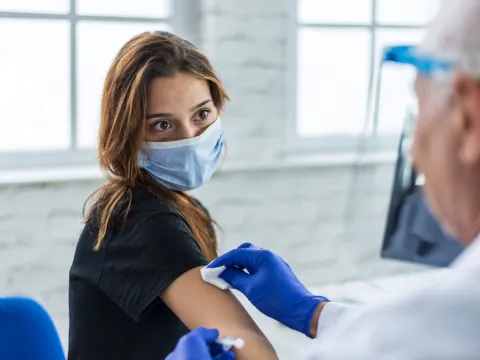 Woman wearing a mask getting her covid-19 vaccine booster shot.