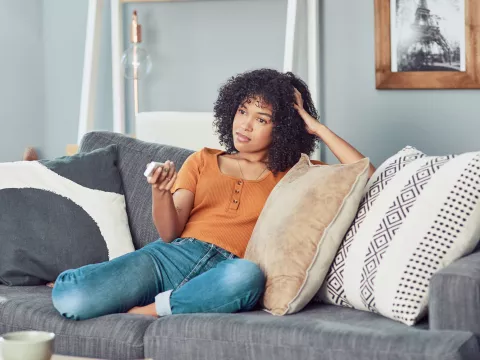 A woman relaxing and watching television at her house