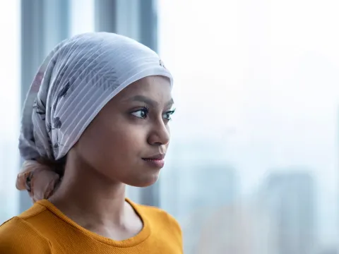 A young woman with cancer staring out the window. 