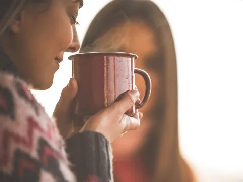 A woman smelling a fresh cup of her tea