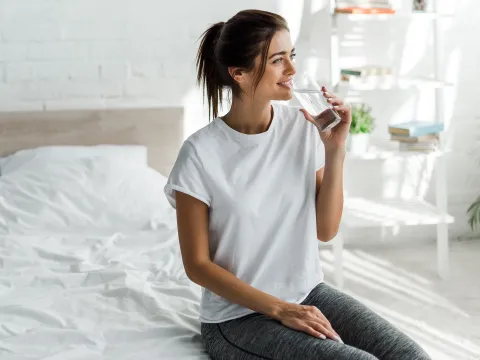 A young woman drinking a glass of water.