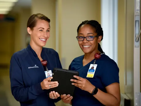 Two nurses from AdventHealth holding a tablet