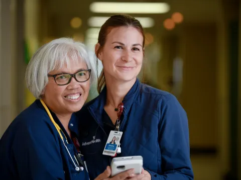 Two nurses from AdventHealth Palm Coast, smiling and looking to the right of the camera