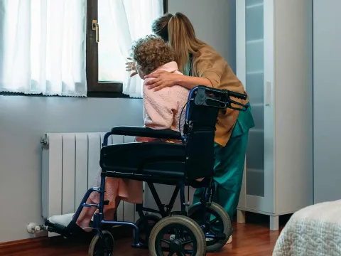 Woman embracing elderly woman in hospice/home care