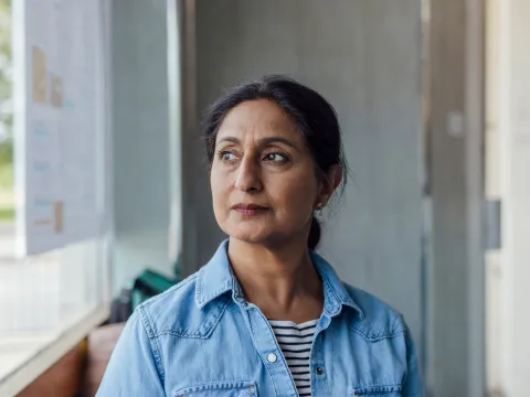 An older woman looking out the window pensively.