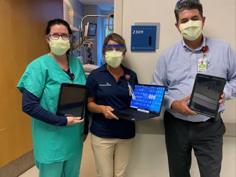 AdventHealth Palm Coast team members Jennifer Mellow, Wendi Coheley and Eddie Conclaves with the tablets used to host a patient's virtual anointing ceremony.