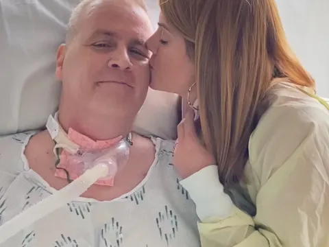 Karen Wilkinson gives her husband David a kiss on the cheek while he's in the hospital.