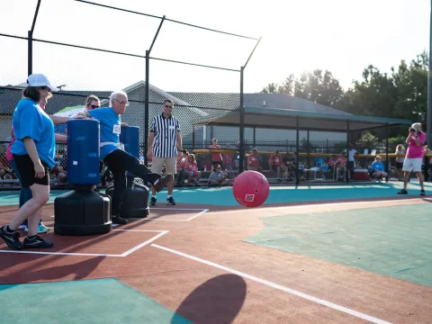 man kicks giant ball to the in field