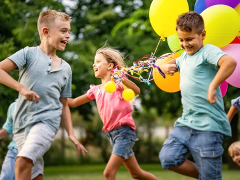 Kids running and playing with balloons