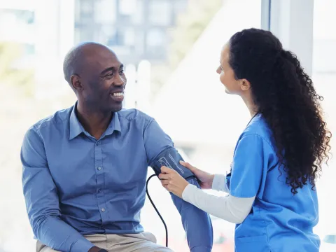 A male patient getting his blood pressure checked by a nurse.