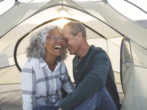 man and woman camping in tent with sun shining