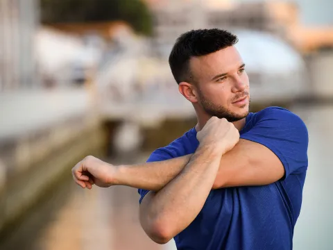 A young man stretching outdoors.