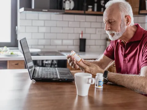 An older man requesting a prescription refill from his computer. 