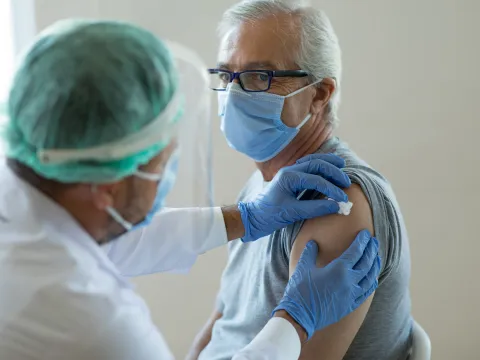 Man getting bandaged after a vaccine while wearing a mask.