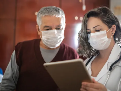 Man looking at chart with a doctor while both are wearing masks.