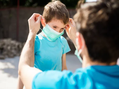 A father puts a mask on his young son.