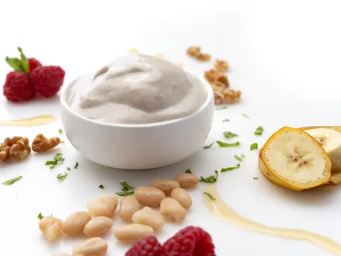 a bowl of homemade vanilla ice cream, surrounded by banana slices, walnut pieces, cannellini beans and raspberries