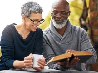 A mature couple reading the bible outdoors