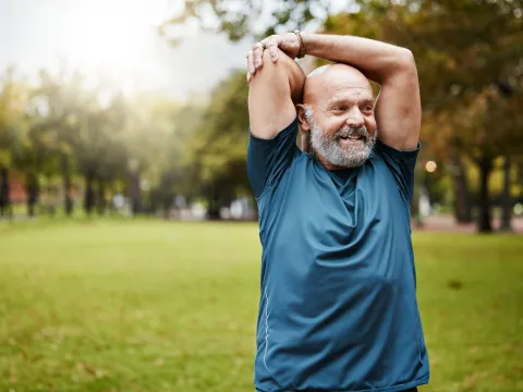 An older man stretching outdoors.