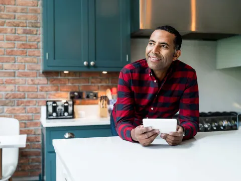 Smiling Man in Home Kitchen with a Tablet