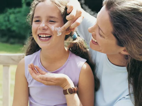 Mom applying sunscreen to daughter