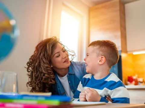 A child laughing as he looks at her smiling mother. 