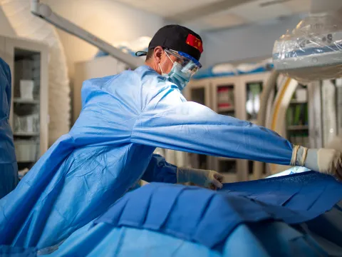 Neurosurgeon placing surgical drape over patient.