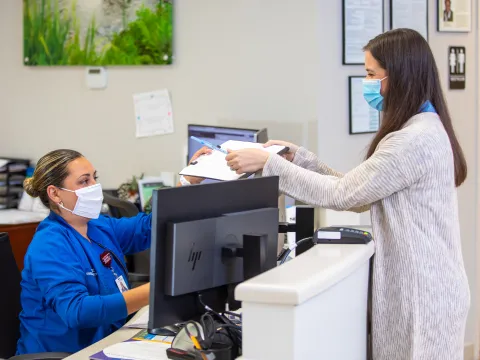 A women checking-in for a neurology appointment with the front desk.