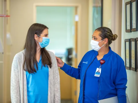 Neurology care team member walking and talking with a patient.